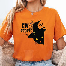 Load image into Gallery viewer, Person wearing an orange t-shirt with a Halloween design featuring a black cat Witchy Catitude ‘Ew People’ Tee - Orange - JBCoolCats
