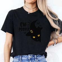 Load image into Gallery viewer, Person wearing an Blackt-shirt with a Halloween design featuring a black cat Witchy Catitude ‘Ew People’ Tee - Black- JBCoolCats