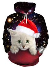 Load image into Gallery viewer, Christmas hoodie featuring a light gray kitten in a red Santa hat resting on a red surface, set against a starry outer space background with bright galaxies. Kitty Cuteness Christmas Hoodie - Front - JBCoolCats