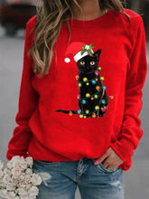 Load image into Gallery viewer, A person wearing a red sweatshirt with a graphic of a black cat wearing a Santa hat and adorned with Christmas lights  Twinkle Paws Christmas Cat Sweatshirt - Christmas - JBCoolCats