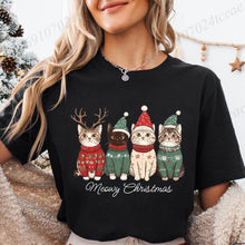 Load image into Gallery viewer, Person wearing a black t-shirt with Christmas-themed cat graphics and 'Meowy Christmas' text. Festive Feline Friends Tee - Clasic Black - JBCoolCats