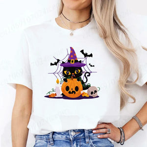 Person wearing a white t-shirt with a Halloween-themed design featuring a black cat, pumpkin, and witch hat.Witchy Whiskers & Pumpkin Pals Tee - JBCoolCats