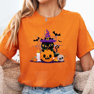 Person wearing a orange t-shirt with a Halloween-themed design featuring a black cat, pumpkin, and witch hat.Witchy Whiskers & Pumpkin Pals Tee - JBCoolCats