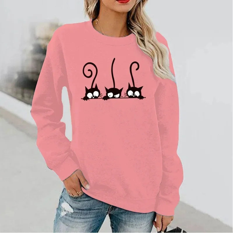 Person wearing a pink sweatshirt with 3 peeking black cats - JBCoolCats