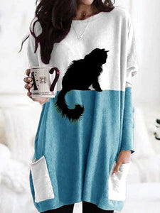 Woman wearing a white and blue dress with a black cat design, holding a mug.   - JBCoolCats