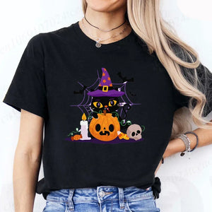 Person wearing a black t-shirt with a Halloween-themed design featuring a black cat, pumpkin, and witch hat.Witchy Whiskers & Pumpkin Pals Tee - JBCoolCats