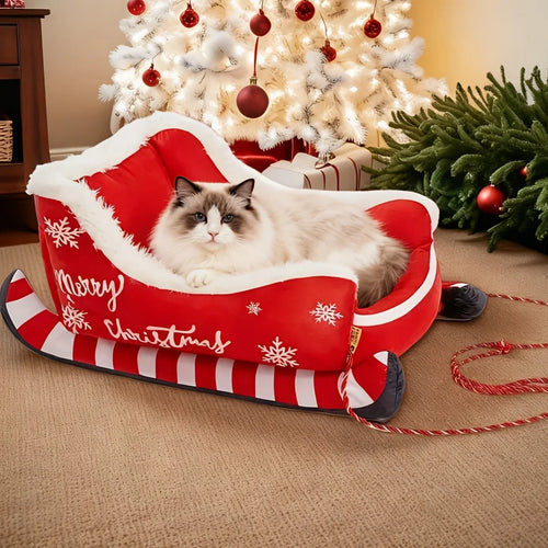 Cat lying on a red Christmas-themed pet bed with a decorated tree in the background - Feline Express Sleigh Bed - Cat Accessories - JBCoolCats