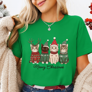 Person wearing a green t-shirt with Christmas-themed cat illustrations and 'Meowy Christmas' text. Festive Feline Friends Tee - Forest Green - JBCoolCats