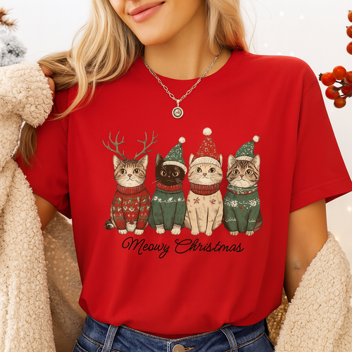 Person wearing a red t-shirt with Christmas-themed cat graphics and 'Meowy Christmas' text. - Festive Feline Friends Tee - Christmas -  Holiday Red JBCoolCats